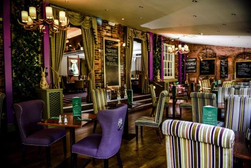 a restaurant with purple chairs and tables in a room at Bowburn Hall Hotel in Durham