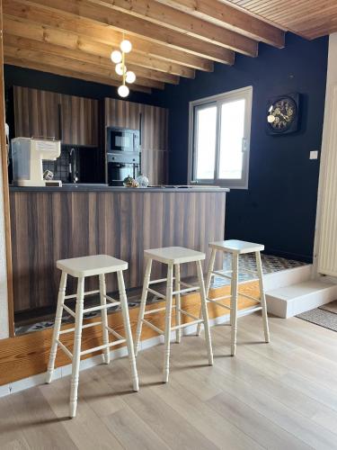 une cuisine avec deux tabourets devant un comptoir dans l'établissement Le Loft Corail, à Jullouville