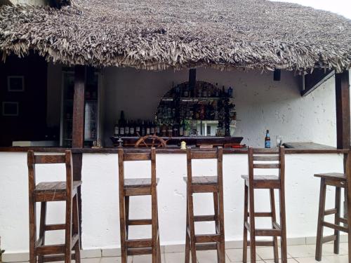 a group of chairs sitting at a bar with a thatch roof at Indri Lodge in Andasibe