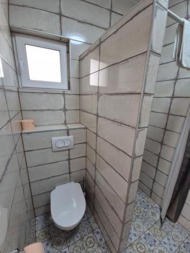 a bathroom with a toilet and a window at Altair Árpád Apartman in Vecsés