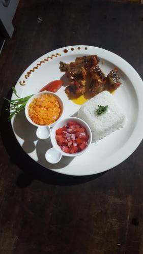 a plate of food with meat and rice on a table at Indri Lodge in Andasibe