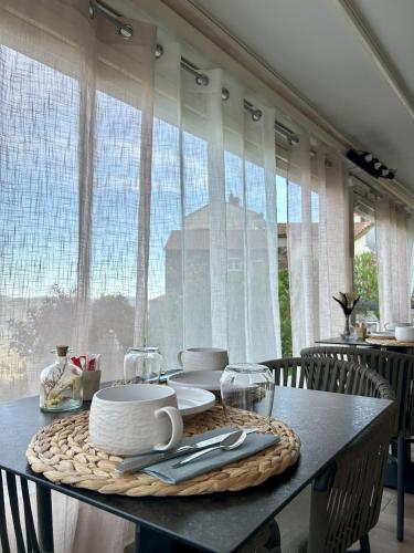une table avec des assiettes et des ustensiles devant une fenêtre dans l'établissement Hôtel Villa Les Orangers, à Olmeto