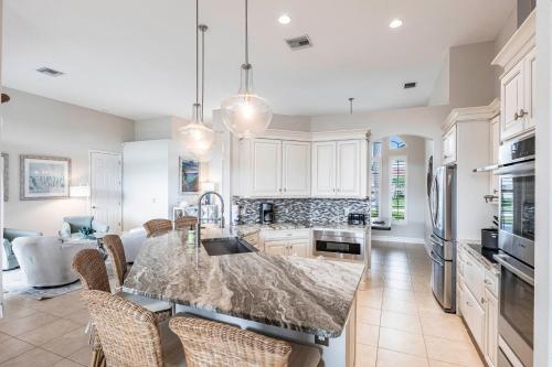 a kitchen with a marble counter top and chairs at Marco Island Majesty in Marco Island