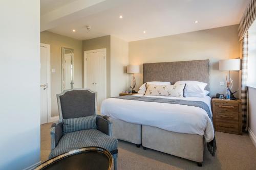 a bedroom with a large bed and a chair at The Gannet Inn in St Ives