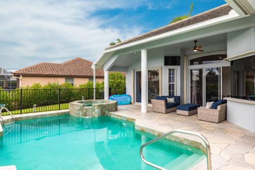a swimming pool with chairs and a house at Marco Island Majesty in Marco Island