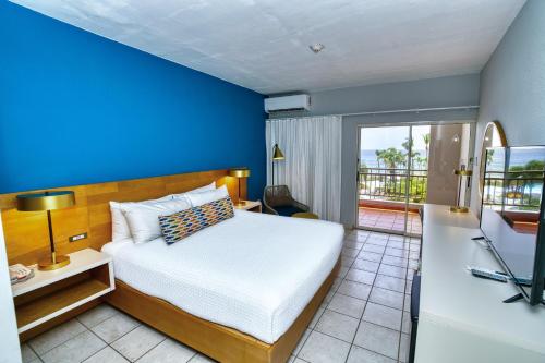 a bedroom with a bed with a blue wall at Rincon of the Seas Grand Caribbean Hotel in Rincon