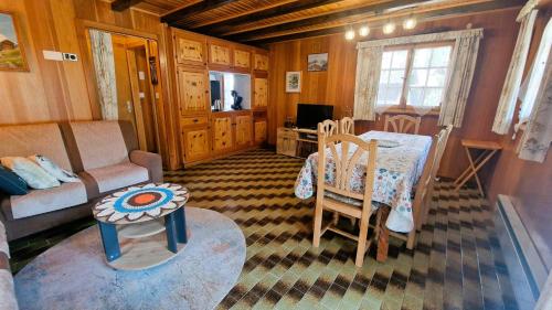 a living room with a table and a couch and a table and chairs at Chalet Lu Verzache 5 personnes in Evolène