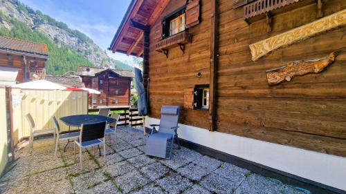 a patio with a table and chairs next to a building at Chalet Lu Verzache 5 personnes in Evolène