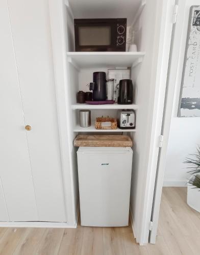 La cuisine est équipée d'un petit réfrigérateur blanc et d'un four micro-ondes. dans l'établissement Studio neuf à 100m de la plage, à Concarneau