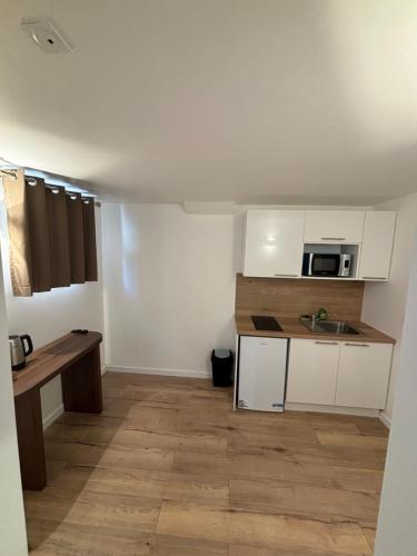 Elle comprend une petite cuisine avec des placards blancs et du parquet. dans l'établissement Pavillon92, à La Garenne-Colombes