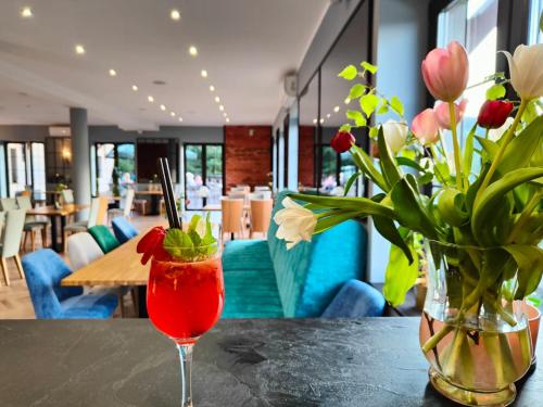 a drink sitting on a table with a vase of flowers at Willa Pod Janowcem SPORT - REST & SPA in Stronie Śląskie