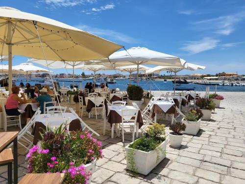 un ristorante con tavoli e sedie con fiori e ombrelloni di Mia House - Appartamento Marzamemi a Marzamemi