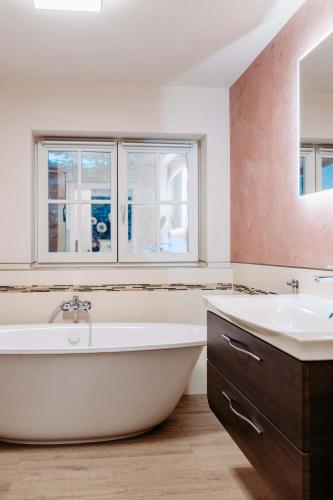 a bathroom with a tub and a sink and two windows at Silberleithen Estate in Biberwier