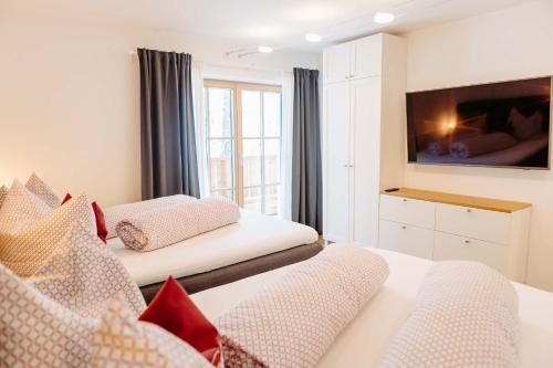 a bedroom with two beds and a tv on the wall at Silberleithen Estate in Biberwier