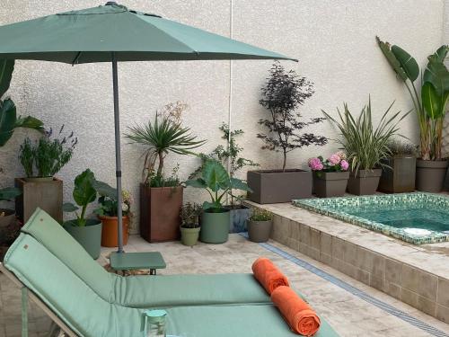 a patio with a couch and an umbrella and a pool at La Hugotine in Marseillan