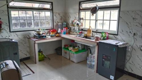 a kitchen with a counter and a sink and two windows at Naufal homestay & kost in Ngemplak