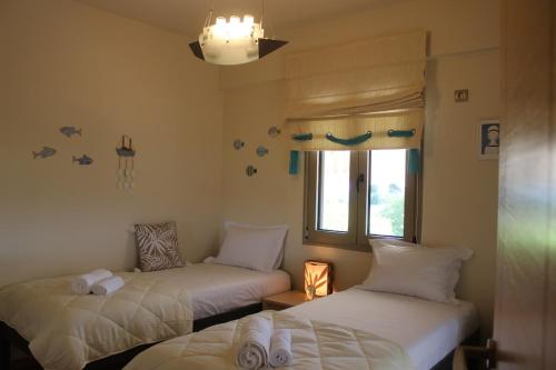 a room with two beds and a window at Villa Polyxeni Magnolia 150m from the sea in Politiká