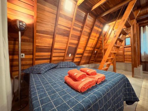 a bedroom with a bed with two orange pillows on it at Chalé Toledo e Costa II in Itapeva