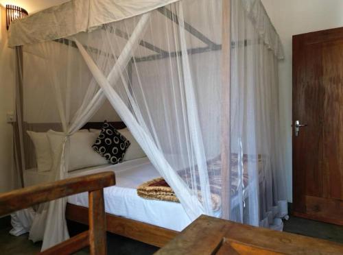 a bedroom with a canopy bed with white curtains at Suna's Place in Ahangama
