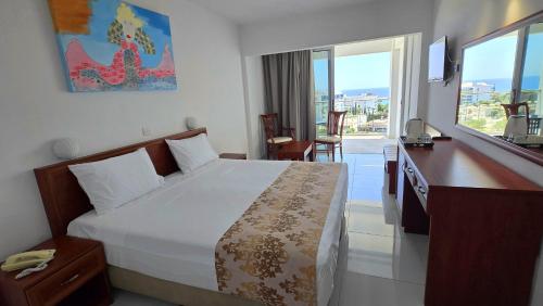 a hotel room with a bed and a desk and window at Corfu Hotel in Ayia Napa