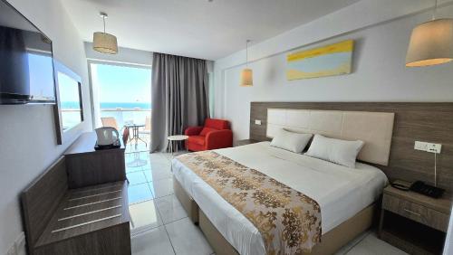 a hotel room with a bed and a red chair at Corfu Hotel in Ayia Napa
