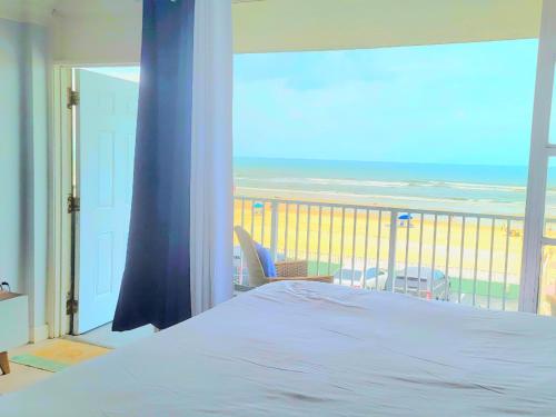a bedroom with a bed and a view of the beach at Direct Oceanfront With Balcony in Daytona Beach