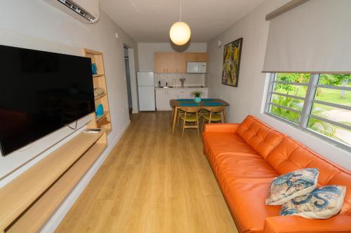 a living room with an orange couch and a flat screen tv at Rincon of the Seas Grand Caribbean Hotel in Rincon
