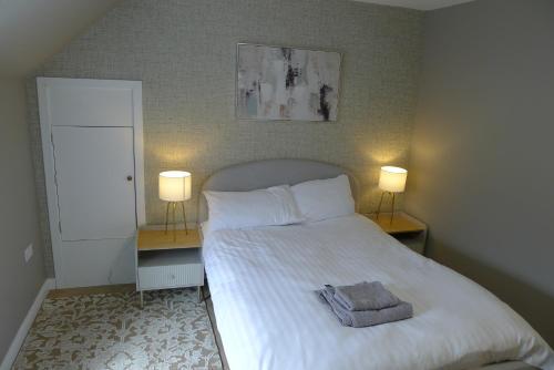 a bedroom with a white bed with two lamps at Hanover st partment in Fraserburgh