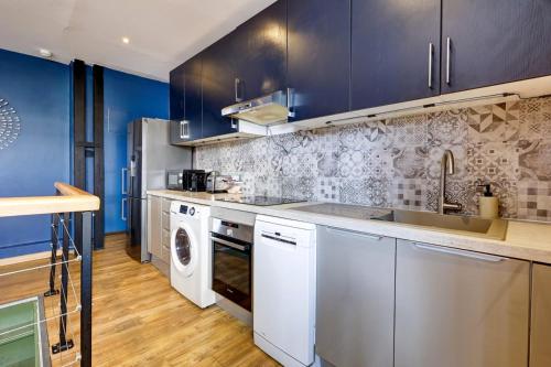 - une cuisine avec des placards bleus et un lave-linge/sèche-linge dans l'établissement Bluestay 226 - Charmant appartement, à Paris