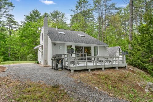 a white cottage with a porch and a grill at Your Trail's End in Maine in Wayne