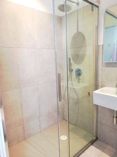 a shower with a glass door next to a sink at Alghero Vacanza in Alghero