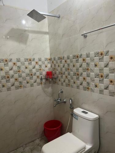 a bathroom with a toilet and a red bucket at Krishna Gopuram Lodge in Guruvāyūr