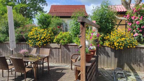 a garden with a table and chairs and flowers on a fence at Küstenblüte in Steffenshagen