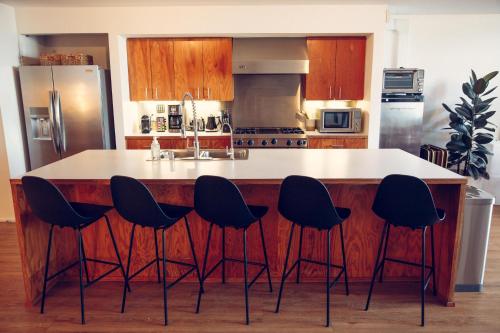 a kitchen with a island with black stools around it at STAY OPEN Venice Beach in Los Angeles