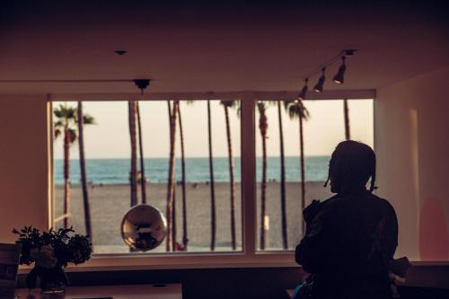 a woman looking out a window at the beach at STAY OPEN Venice Beach in Los Angeles