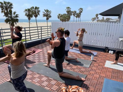 a group of people doing yoga at the beach at STAY OPEN Venice Beach in Los Angeles
