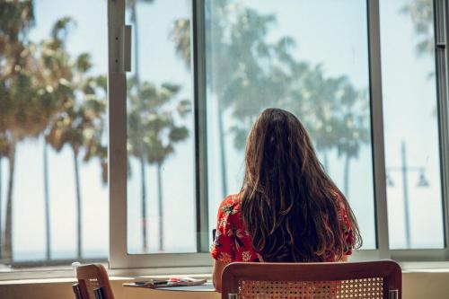 a woman sitting in a chair looking out of a window at STAY OPEN Venice Beach in Los Angeles