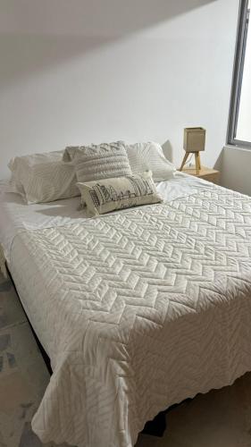 ein Bett mit einer weißen Bettdecke und Kissen darauf in der Unterkunft Apartamento en Paipa - Boyacá in Paipa