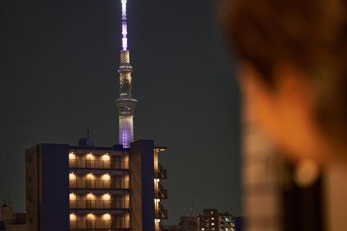 a man looking at the berlin tv tower at night at brand-new hotel, a 3-minute walk from Asakusa Kuramae Statio in Tokyo