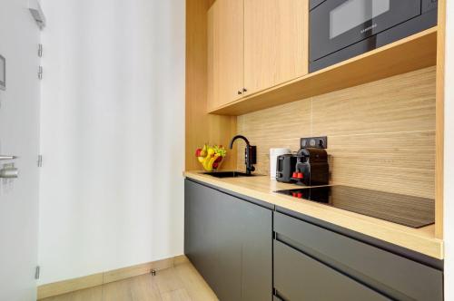une cuisine avec des armoires en bois et un comptoir dans l'établissement Bluestay 288 - Superbe studio à Paris 17, à Paris