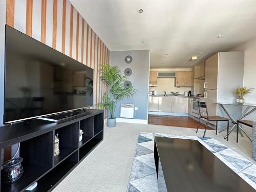 a living room with a large television and a table at Seaside APT with Harbour View in Swansea