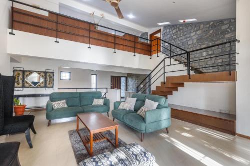 a living room with two couches and a staircase at Grandeur Villa by StayJade Huge Garden 5BHK in Yelahanka