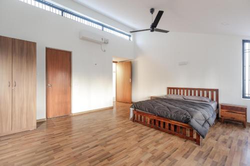 a bedroom with a bed and a wooden floor at Grandeur Villa by StayJade Huge Garden 5BHK in Yelahanka