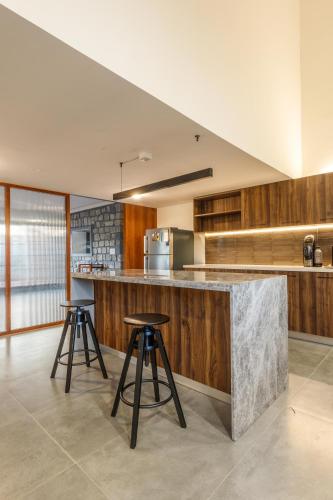 a kitchen with two bar stools and a counter top at Grandeur Villa by StayJade Huge Garden 5BHK in Yelahanka