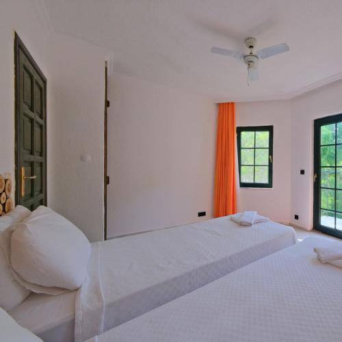 a white bedroom with two beds and an orange curtain at Club Mel Holiday in Ortaca