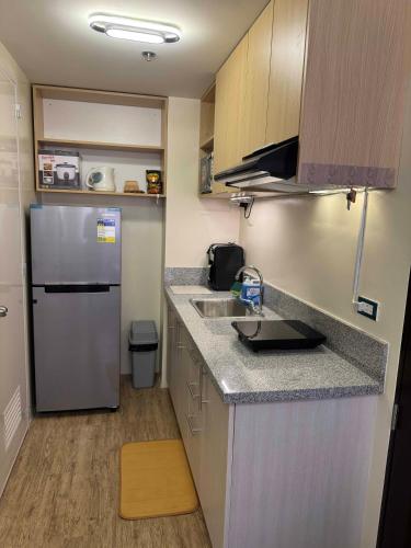 a small kitchen with a refrigerator and a sink at Berkeley Suites, Silang Cavite in Silang