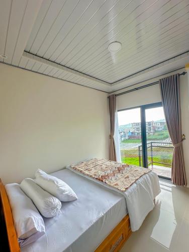 ein Bett in einem Zimmer mit einem großen Fenster in der Unterkunft The Tjokro Villa Dieng in Diyeng