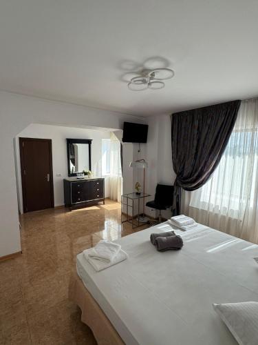 a bedroom with a white bed and a living room at Pensiunea Diamond in Eforie Nord