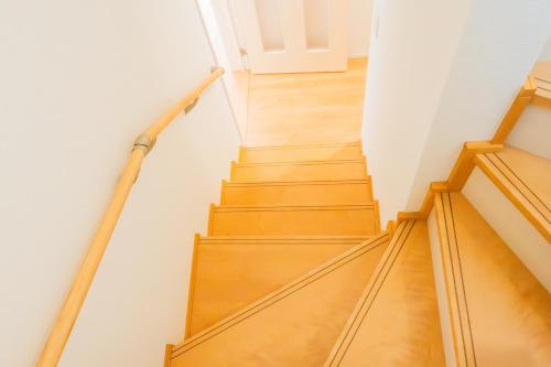 a staircase with wooden floors and a white wall at IBUNOYA Yaese in Yaese