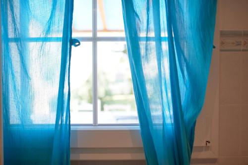 a window with blue curtains in a bathroom at Cà del Mar rustico a Jesolo con giardino e piscina privati ad uso esclusivo # in Jesolo